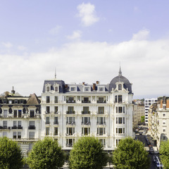 Exterior facade of The Woodward Geneva, a grand lakeside hotel with classic architecture and tree-lined streets.