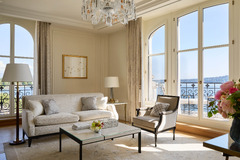 Elegant living room with neutral tones, large windows, and lake views at The Woodward Geneva suite.