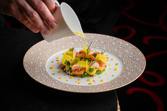 Gourmet dish being artfully plated at L’Atelier Robuchon, emphasizing culinary precision and luxury presentation.